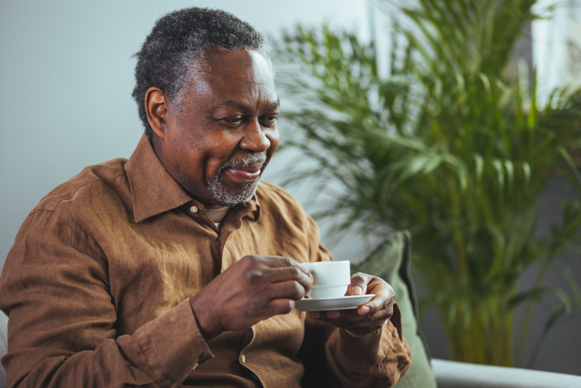 A senior man enjoys a cup of coffee at home.
